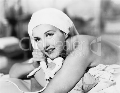 Young woman lying on the bed and talking on the telephone
