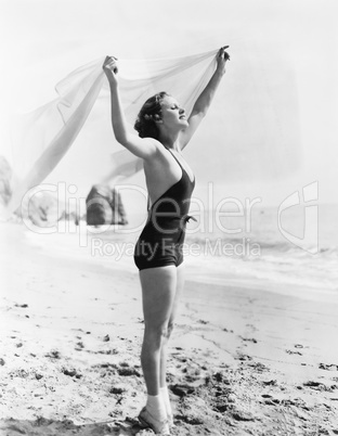 Profile of a young woman holding up a sarong at the beach