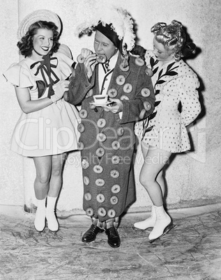 Man in an outfit made of donuts standing between two teenage girls