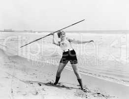 Young woman preparing to throw a javelin on the beach