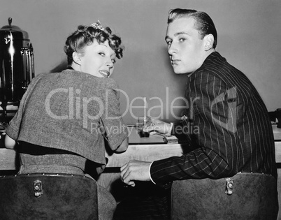 Portrait of a couple sitting on a counter and looking over their shoulders