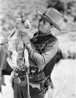 Cowboy carrying a lamb and smiling