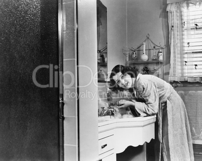 Profile of a young woman washing her hands in the bathroom sink