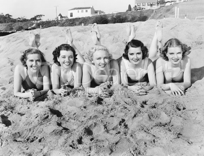 Portrait of five young women lying on the beach and smiling