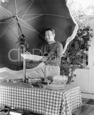 Man standing at a picnic table and holding a plate