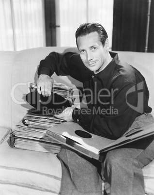 Portrait of a man sitting on a couch and taking out a record from his collection