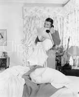 Young man talking on the telephone and biting into a pillows