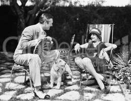 Couple sitting in the back yard talking with a dog between them