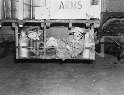 Two boys with milk canisters in a cargo bay of a truck