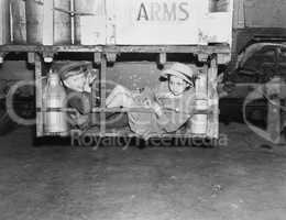 Two boys with milk canisters in a cargo bay of a truck