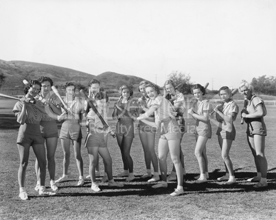 Group of women holding baseball bats and standing in a row