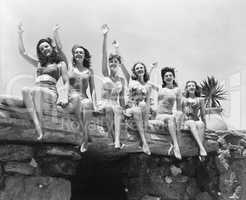 Low angle view of a group of women sitting on a stone structure and waving their hands