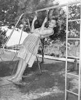 Profile of a young woman swinging on a swing in a garden