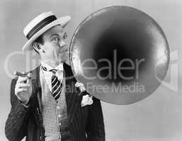 Man holding a cigar and standing near a victrola horn