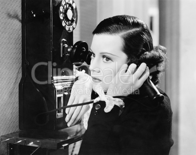 Profile of a young woman talking on a payphone