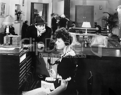 Profile of a woman working on the telephone switchboard with a man looking at her