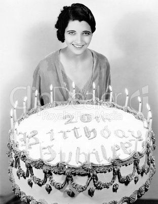 Portrait of a young woman standing in front of a birthday cake