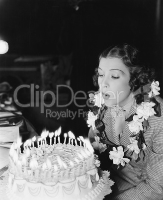 Profile of a young woman blowing off candles on a birthday cake