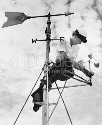Low angle view of a young woman mending a weather vane