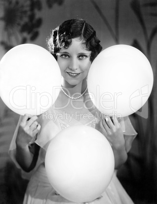 Portrait of a young woman balancing balloons on her hands and knees