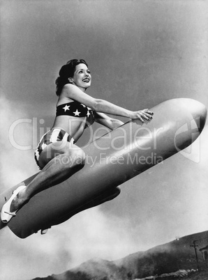 Low angle view of a young woman sitting on a rocket and smiling