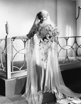 Young woman standing in wedding dress and holding a bouquet of flowers