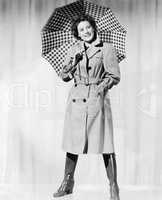Woman in rain gear holding an umbrella and smiling