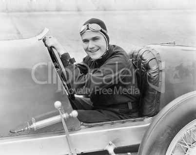 Young man sitting in a race car with a big smile
