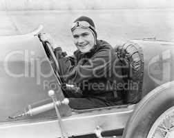 Young man sitting in a race car with a big smile