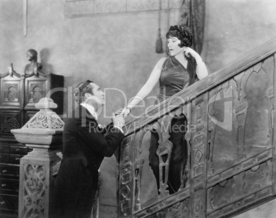 Man holding the hand of a woman standing on a staircase