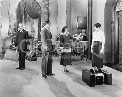 Four people standing in a the lobby of a hotel with luggage
