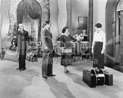 Four people standing in a the lobby of a hotel with luggage