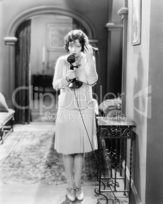 Woman standing in the hallway talking on a candlestick telephone