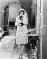 Woman standing in the hallway talking on a candlestick telephone
