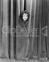 Woman peek-a-booing behind a curtain