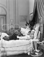 Woman and poodle sitting next to an injured man in bed