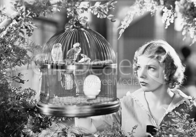 Woman looking into a bird cage with birds