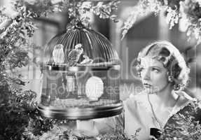 Woman looking into a bird cage with birds
