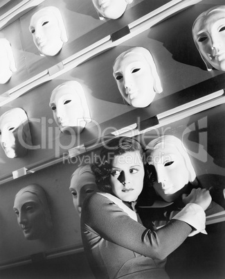 Woman looking frightened holding onto one mask on the wall of masks