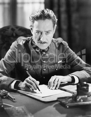 A soldier writing a letter with a gun next to him