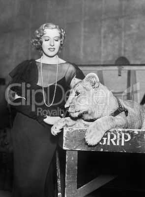 Elegant woman standing next to a lion