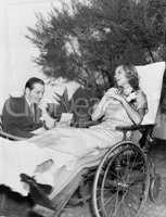 Woman in a wheelchair listening to a man reading a letter