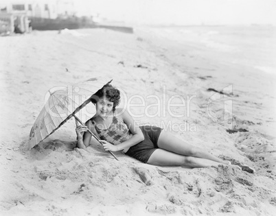 Woman lying at the beach with a sun umbrella