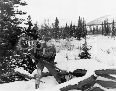 Hunter with his rifle walking through snow covered countryside