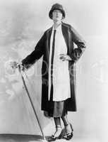 Woman with a walking stick in an elegant dress and coat