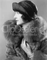 Profile of an elegant woman in a fur coat and satin hat