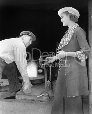 Woman weighing a piece of iron at a foundry