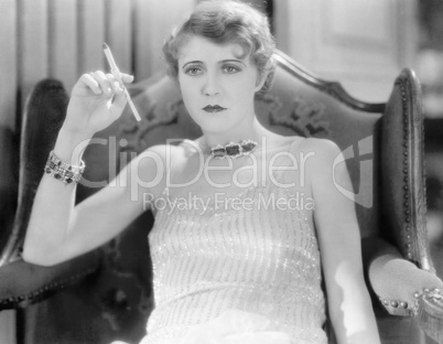 Elegant woman in an evening dress and jewelry smoking a cigarette