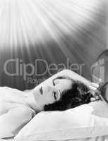 Woman sleeping in a bed with rays of light shining on her