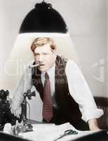 Man leaning over a desk with a ceiling light shining on him